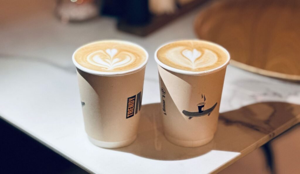 Two cups of latte with beautiful heart-shaped latte art on a café table.